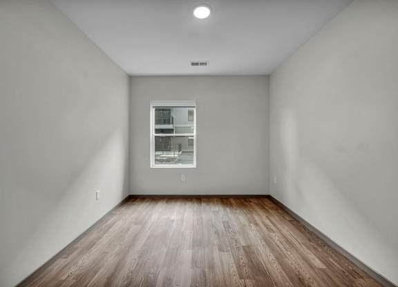 A room with a window and wooden flooring.