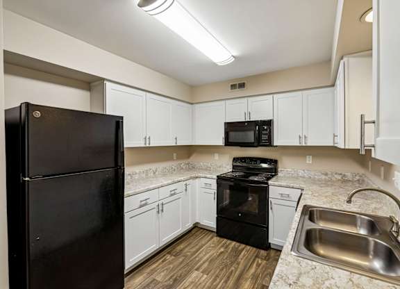 A kitchen with black appliances and white cabinets.