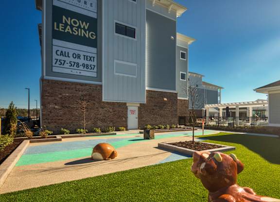 A leasing sign in front of a building with a pool and a statue of a dog.