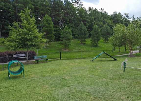 A playground with a green slide and a green swing set.
