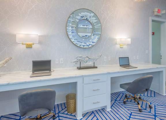 A white desk with a laptop and a clock on the wall.