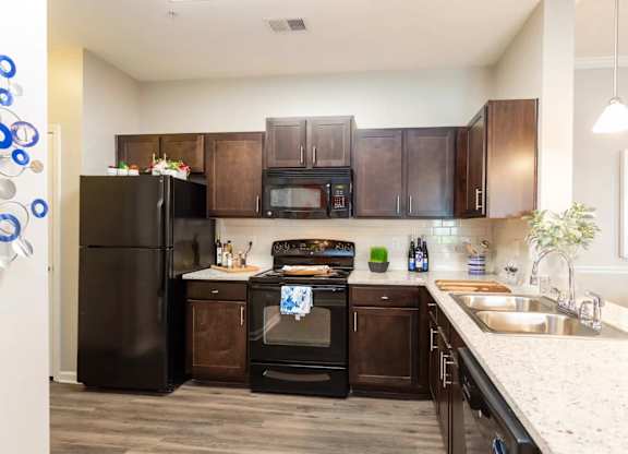 A kitchen with black appliances and brown cabinets.
