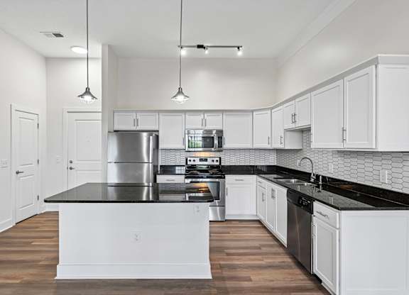 A modern kitchen with white cabinets and a black countertop.