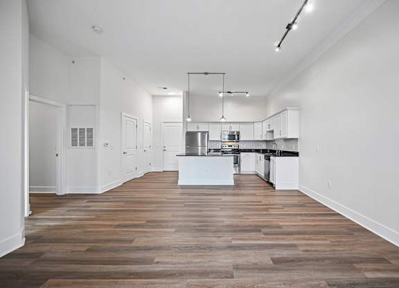 A kitchen with white cabinets and a wooden floor.