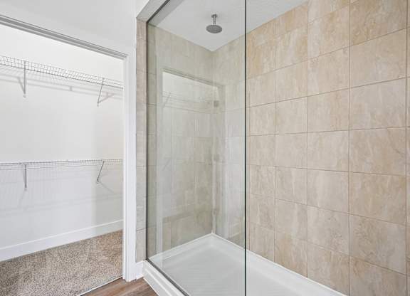 A bathroom with a walk-in shower and a glass door.
