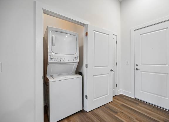 A white vintage television set is sitting in a small room with two doors.