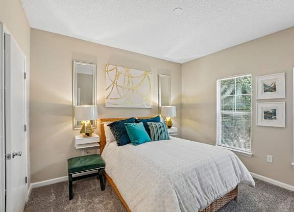 A bedroom with a bed, nightstand, and window.