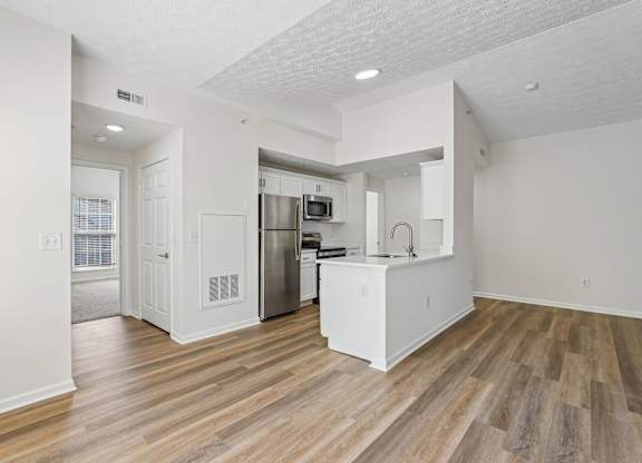 A kitchen with white cabinets and a wooden floor.