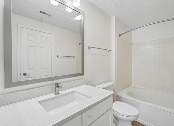 A white bathroom with a sink, toilet, and bathtub.