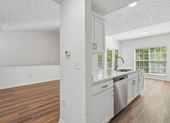 A kitchen with white cabinets and a stainless steel dishwasher.