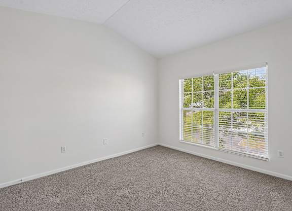 A room with a window and carpeted floor.