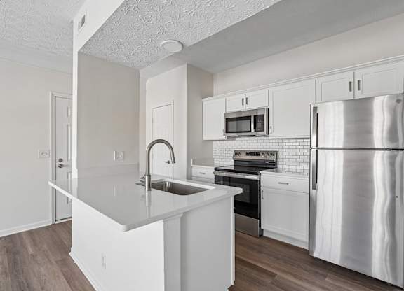 A kitchen with white cabinets and a stainless steel refrigerator.