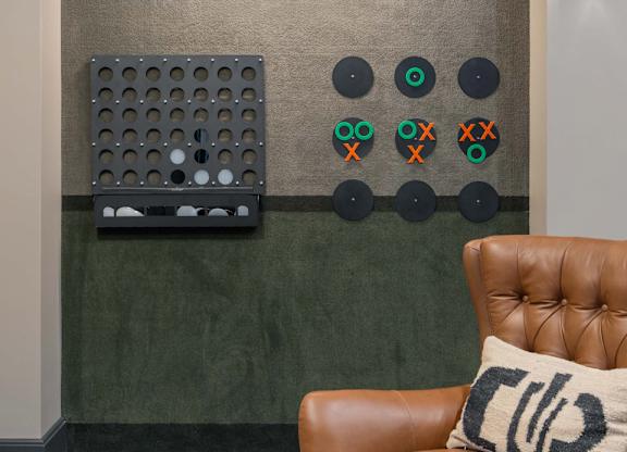A brown leather chair with a pillow on it in front of a wall with a green board and some circles on it at Orleans Apartments, OH, 43221