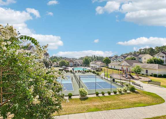 A tennis court is surrounded by houses and trees.