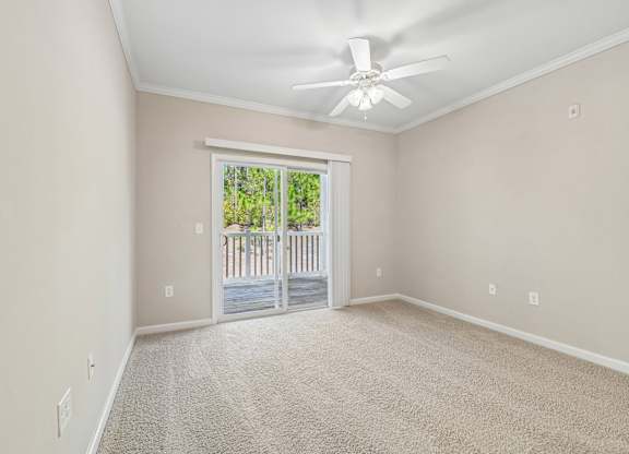 A room with a ceiling fan and a door leading to a balcony.