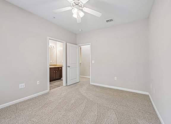 A room with a carpeted floor and a ceiling fan.