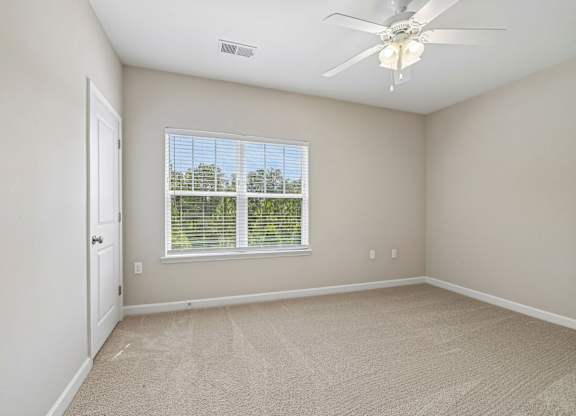 A room with a ceiling fan and a window with blinds.