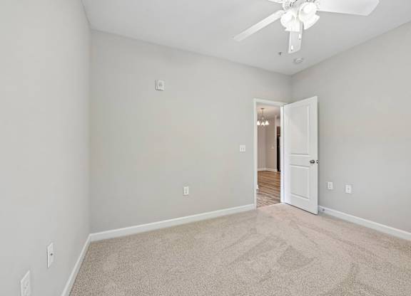 A room with a carpeted floor and a ceiling fan.