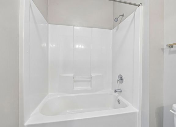 A white bathroom with a tub and toilet.