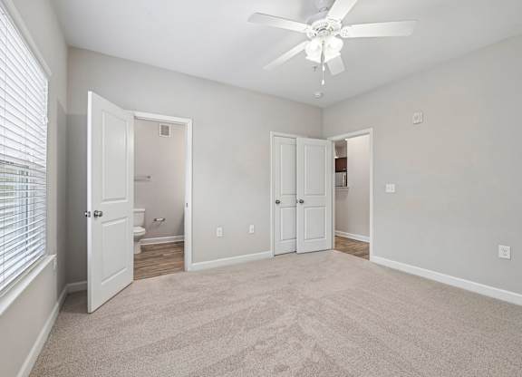A room with a ceiling fan and carpeted floor.