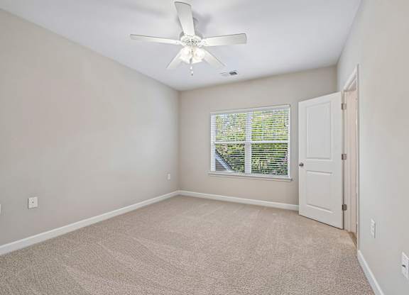 A room with a ceiling fan and a window with blinds.