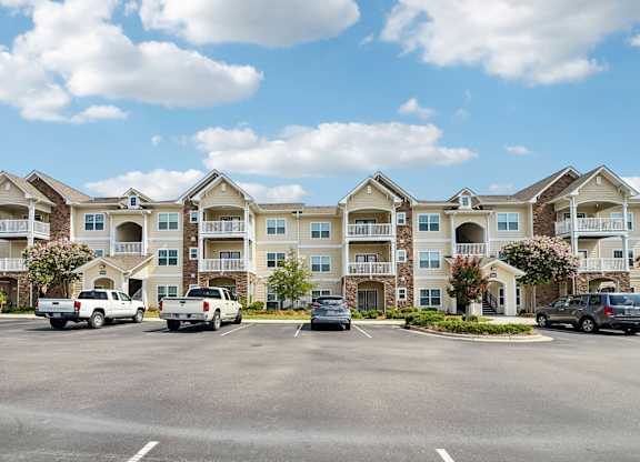 A row of townhouses with cars parked in front.