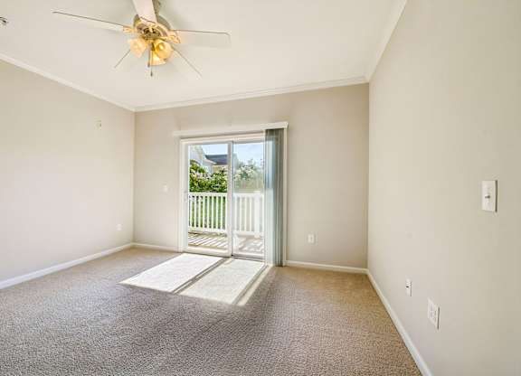 A room with a ceiling fan and a door leading outside.