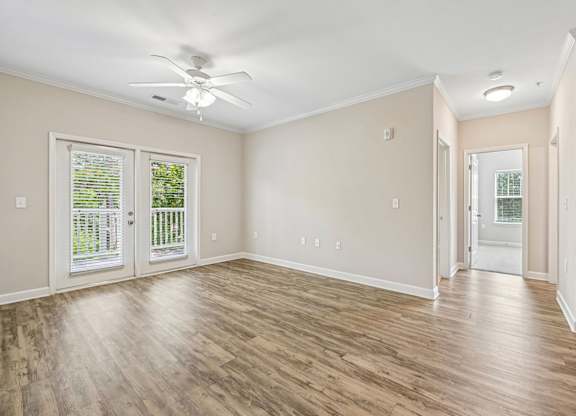 A room with a ceiling fan and sliding glass doors.