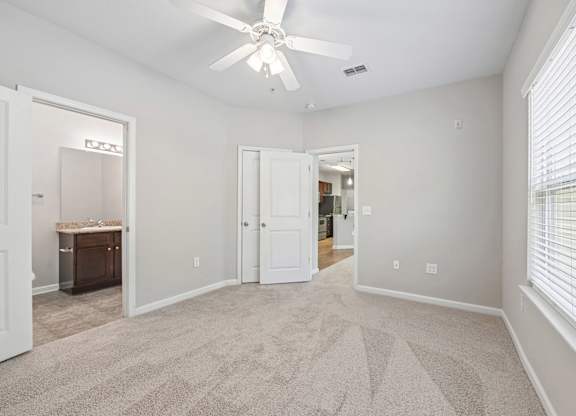 A room with a carpeted floor and a ceiling fan.