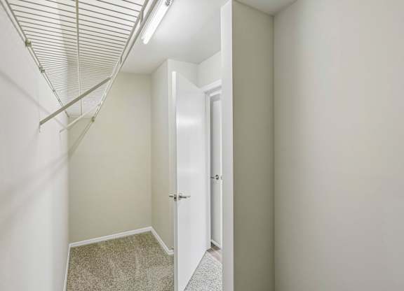 A hallway with a carpeted floor and a white door.