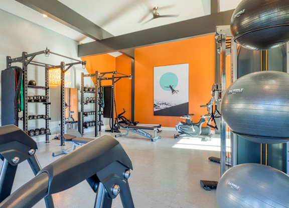 A gym with orange walls and a variety of equipment.