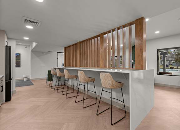 A long white table with chairs and a white counter in a room.