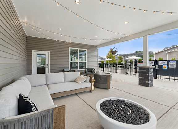A modern outdoor living space with a grey sofa and a fire pit.