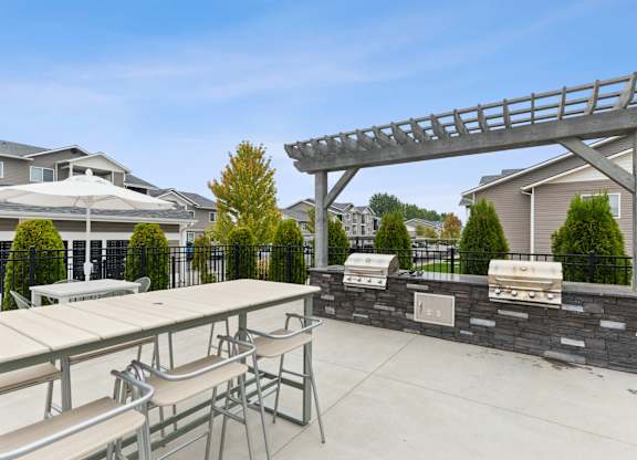 A patio with a table, chairs, and a grill.