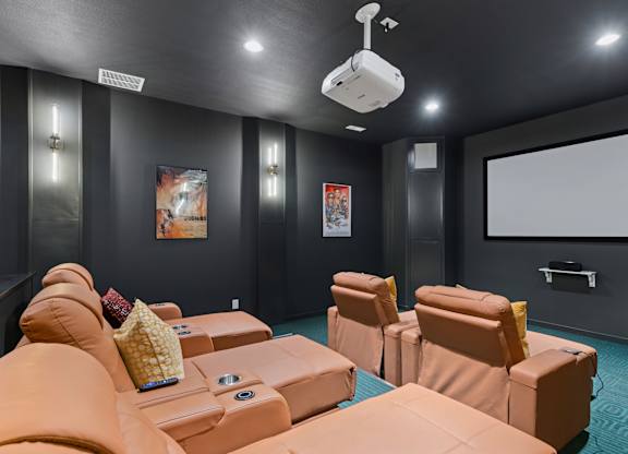A home theater with orange couches and a large screen.