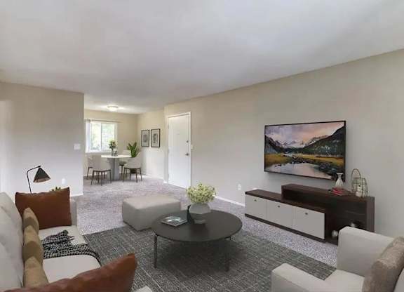 A living room with a grey carpet and a painting on the wall.
