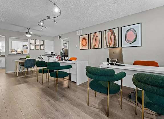 A room with a desk, chairs and pictures on the wall.