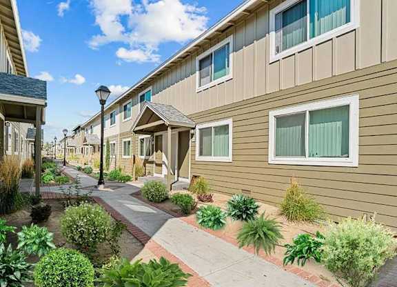 A row of houses with a sidewalk and landscaping in front.