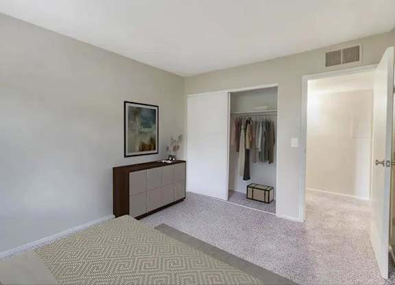 A room with a carpeted floor and a wooden cabinet with a painting on top.