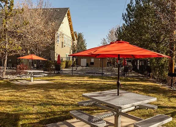 A picnic area with a red umbrella and benches.