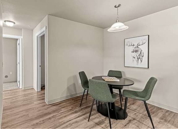 A room with a table and chairs and a moose picture on the wall.