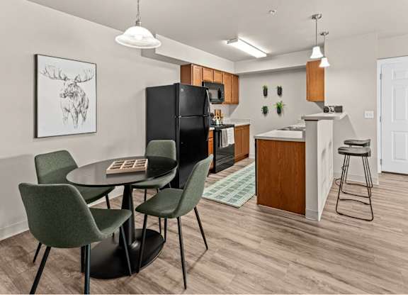 A kitchen with a black fridge, brown cabinets, and a white door.
