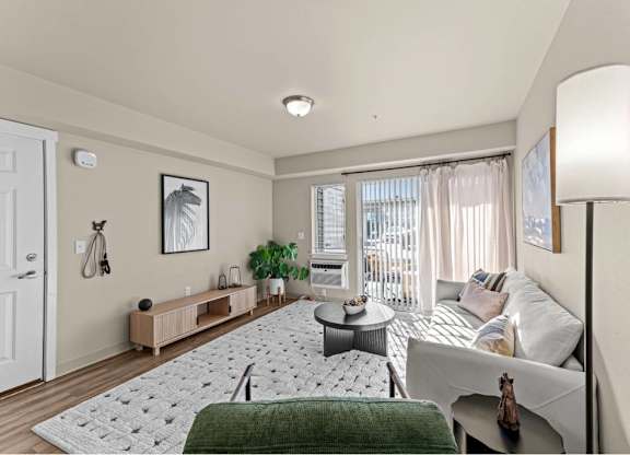 A living room with a grey couch and a green blanket.