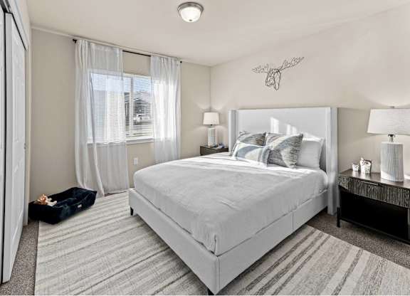 A bedroom with a large bed and a window with curtains.