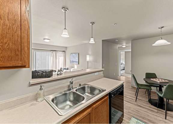 A kitchen with a sink, dishwasher, and a table with chairs.