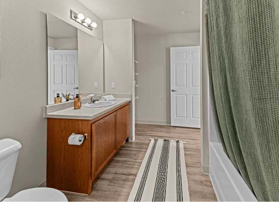A bathroom with a wooden vanity and striped rug.