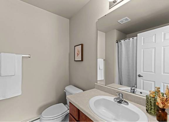 A bathroom with a toilet, sink, and mirror.