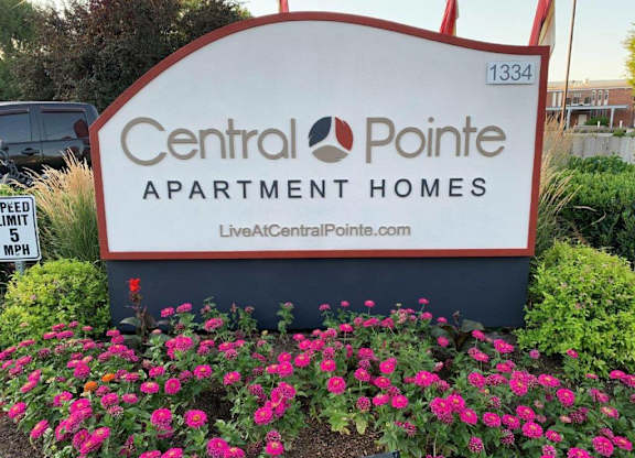 A sign for Central Pointe Apartment Homes is surrounded by flowers.