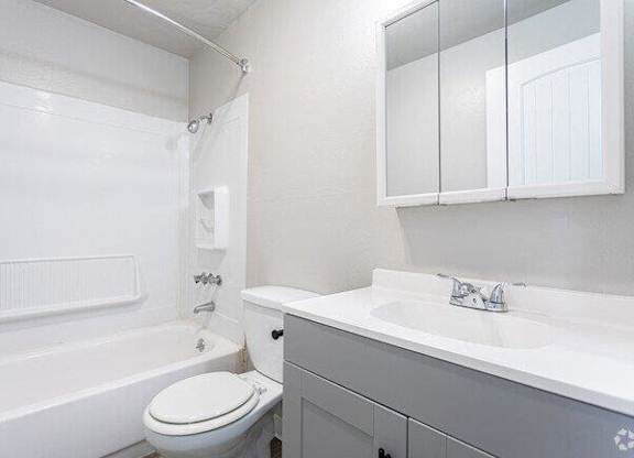 A white bathroom with a toilet, sink, and bathtub.