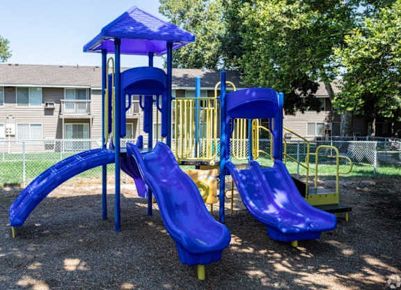 A playground with a blue slide and a yellow slide.